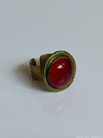 Ring angled view showing red glass cabochon and brass setting