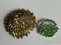 Both brooches side by side showing size difference and colours