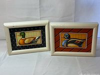 Both framed needlework panels side by side