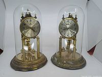 Both Solar torsion clocks under glass domes side by side
