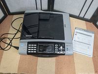 Printer closed with power cord and manual visible