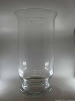 full view of clear glass vase showing cylindrical body, footed base, flared rim