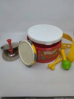 Full set showing drum, lid, shoulder strap, cymbals, tambourine, drumsticks, maraca