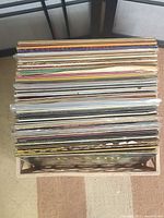 Stack of approximately fifty LP records in wooden crate