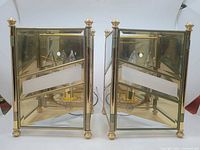 Pair of brass wall sconces, front view showing glass panels, brass frame, sockets