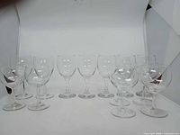 Front view of all 13 clear glass wine glasses in two rows