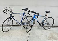 Both road bikes leaning against wall