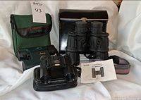 All three binoculars with their cases and manual displayed on white background