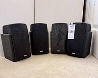 Front view of four identical RCA bookshelf speakers with grilles