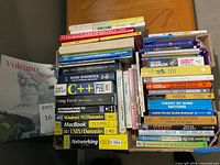 Cardboard box containing numerous assorted books showing spines and titles
