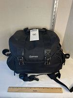Black Canon camera bag with Canon logo and ruler for scale