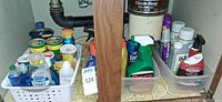 Overall view of two baskets under sink containing assorted cleaning products