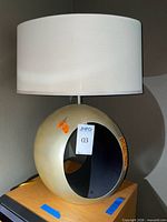 Front view of lamp showing gold cut-out base and white drum shade