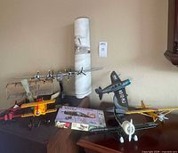 Group view of rolled print, five model airplanes, and boxed kit on tabletop