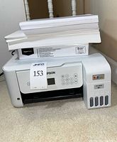 Front view of Epson ET-2800 printer with extra paper stacked on top