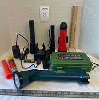 Group shot showing all flashlights, charger, case and accessories with measuring scale