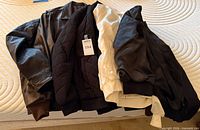 All five bomber jackets laid out on bed