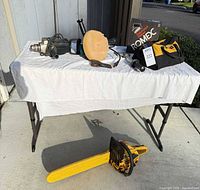 Overall view of lot on table including polisher, floor scraper, wire roll, axe head, chainsaw