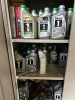 Shelves with multiple Mobil 1 bottles, white bottle, jack stand pieces visible