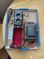 Top view of both cameras in box with their leather cases