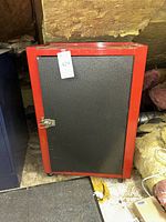 Front view showing black door, red frame, latch, overall wear