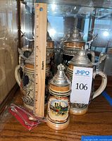 Group of four German beer steins with ruler for scale