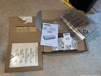 Open box showing laminator inside protective wrap, manual, and loose pouches