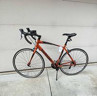 Full side view of orange Tommaso Imola road bike showing frame, handlebars, wheels, and kickstand