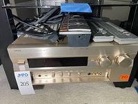 Front view of Yamaha DSP-A1 amplifier with cables and remotes on top