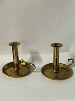Both brass chamberstick candle holders side by side
