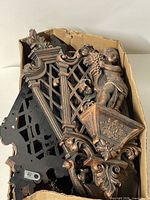 Box containing multiple bronze-finish plastic wall plaques of various designs