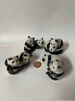 Front view of all four panda figurine pairs with penny for scale