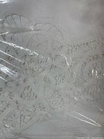Packaged white embroidered tablecloth showing cutwork detail
