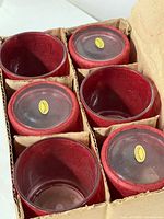 Six red paper maché votive holders in box, top view