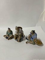 Front view of three ceramic mudmen figurines