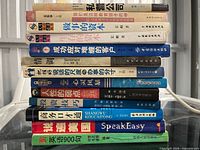 Full vertical stack of approximately 15 Chinese paperback books on tabletop