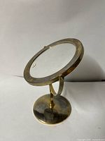 Full view showing brass-tone pedestal and round mirror