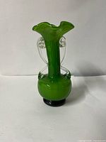 Front view of green art glass vase showing applied clear glass loops and ruffled rim