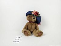 Front view of bear sitting upright showing overall appearance, hat, bow, and tag number