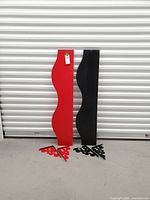 Red and black wavy shelves standing upright with matching brackets on floor