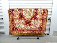 Full view of ornate burgundy velvet bedspread on rack