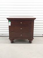 Front view of mahogany chest showing three drawers, brass pulls, and ball feet