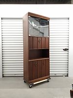 Full view of tall teak wall unit on casters, doors closed