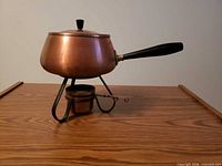 Side view of brass fondue pot on stand with burner