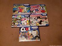 All five Giant Edition board games laid out: Sorry!, Guess Who?, The Game of Life, Monopoly, Clue
