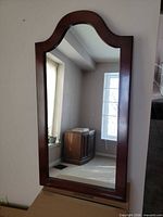 Front view of wood framed mirror showing arched top and glass