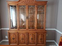Front view of entire china hutch showing glass upper section and wood lower cabinet