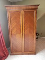 Front view of closed wood entertainment armoire cabinet