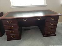 Front view of cherry executive desk showing drawers and brass pulls