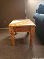 Front view of square wood side table showing turned legs and drawer